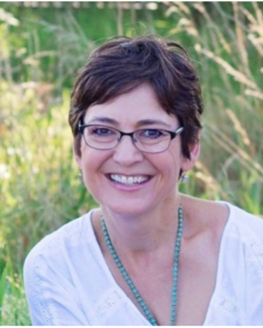 Shelley Gladden: Woman with short dark brown hair and glasses in a grasslands environment